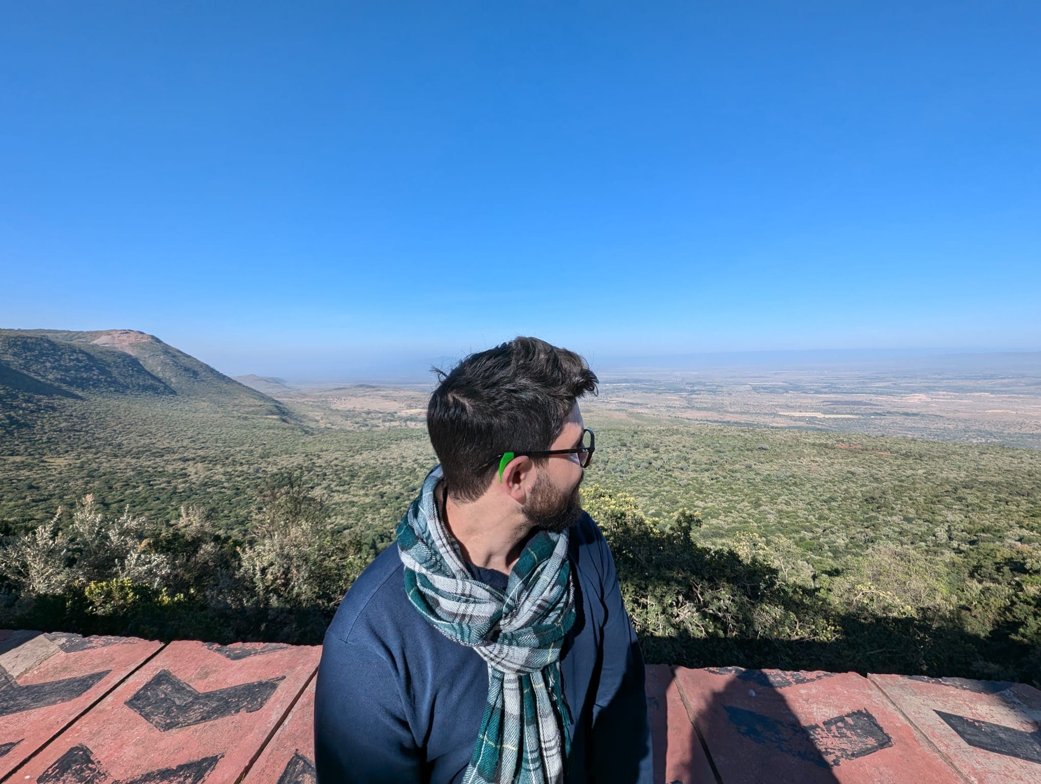 Matteo Tegnenti seduto di spalle sulla Rift Valley in Kenya, con la savana che si estende all'orizzonte